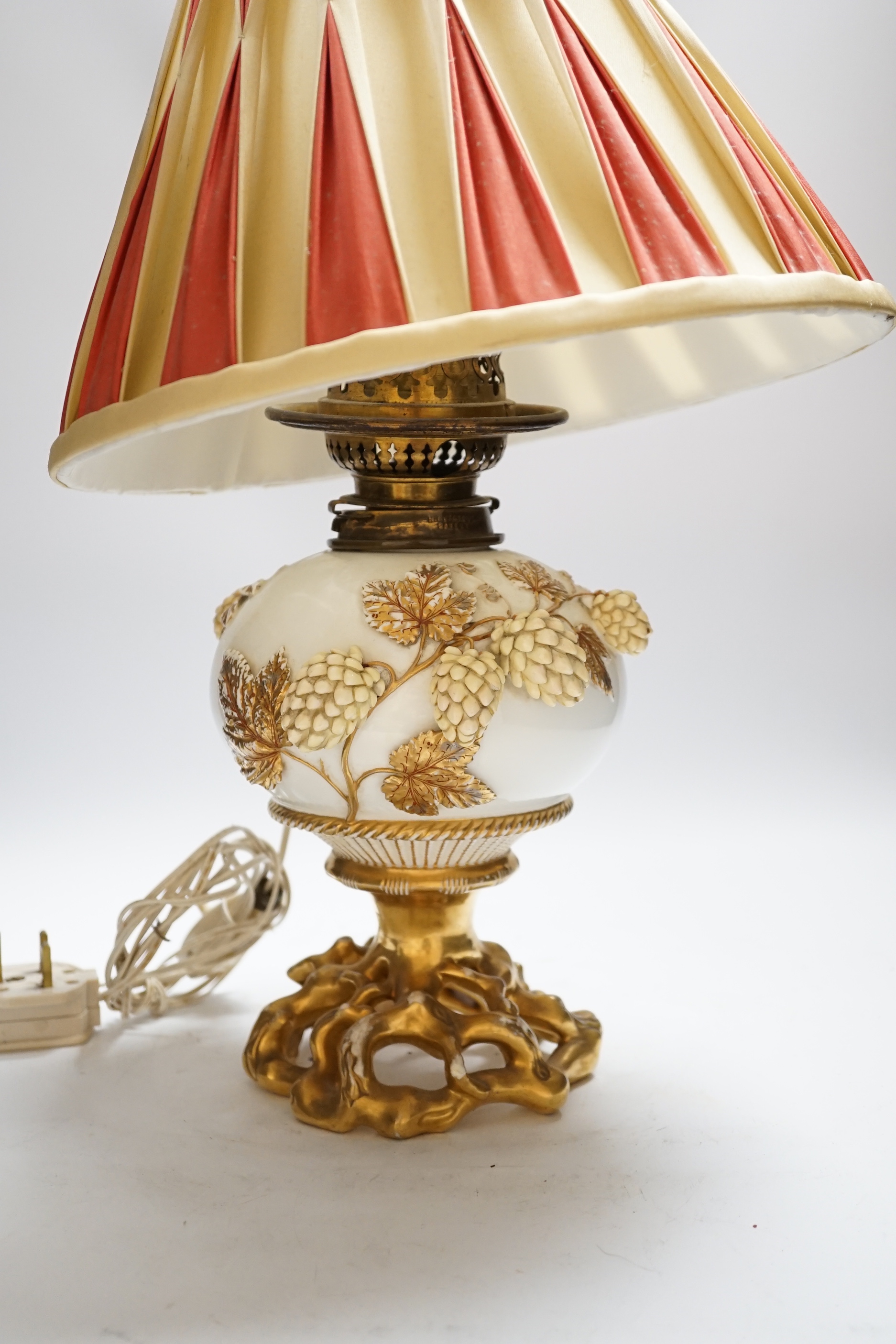 A Victorian porcelain oil lamp, probably Moore brothers, decorated with hops and gilt base, converted to electric, 45cm high